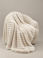 Stretch Plush Faux Fur Blanket draped over a boucle chair