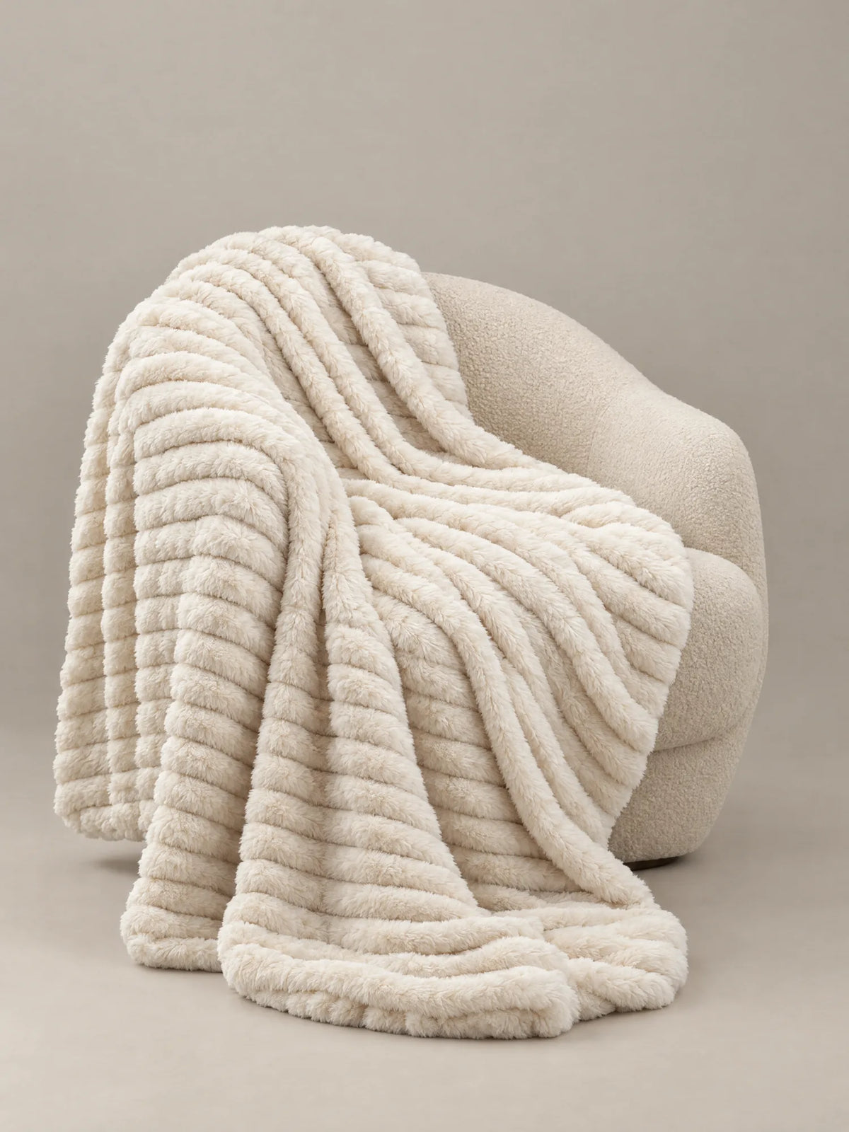 Stretch Plush Faux Fur Blanket draped over a boucle chair
